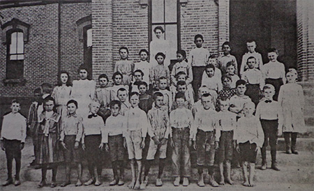 A group of students stands in front of their school in the early days of TUSD.
